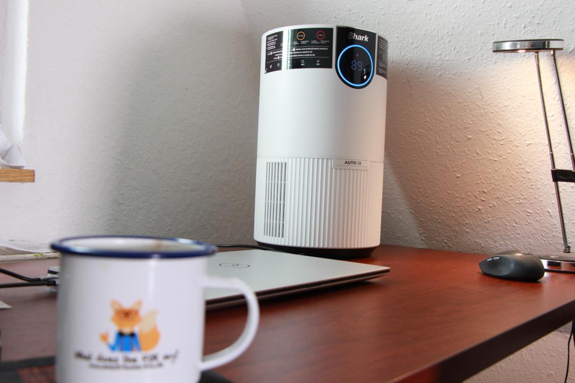 Der Shark HP100 EU Luftreiniger steht im Test auf einem Bürotisch neben einem Laptop.